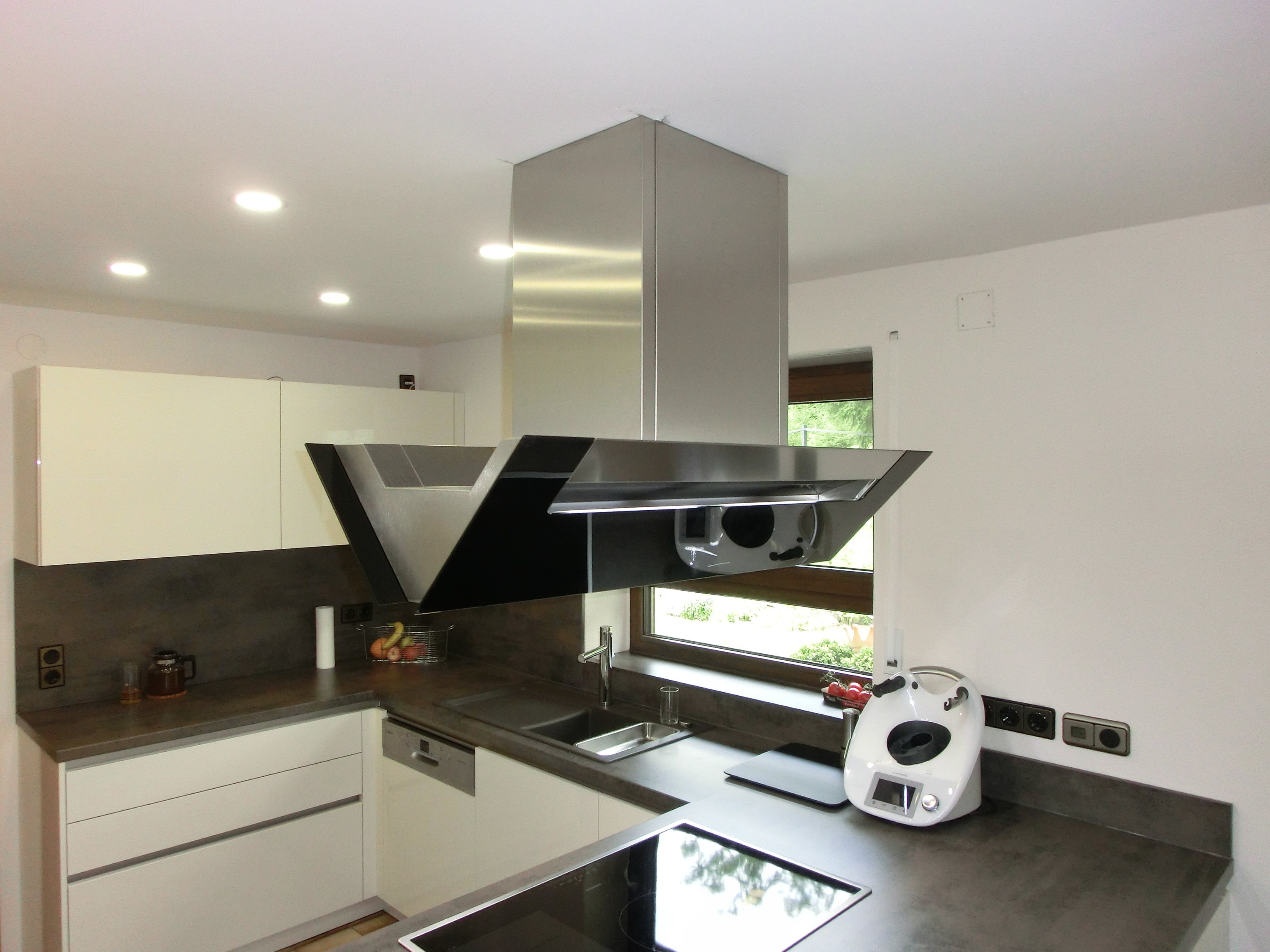 Weiße Küche mit schwarzer Schräghaube und Beton-Arbeitsplatte