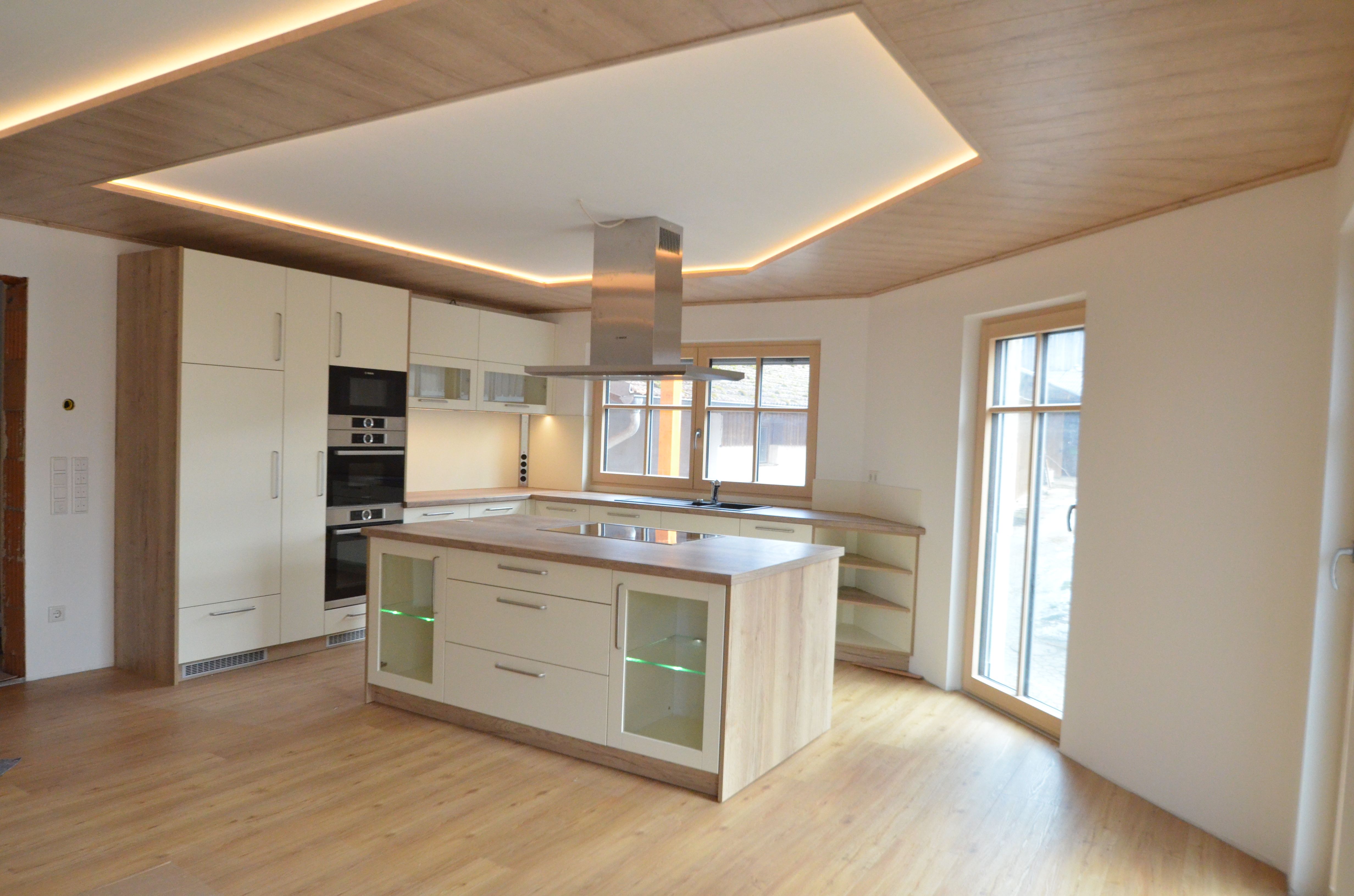 Cremeweiße Küche mit Holzdecken-Insel und LED-Unterbau