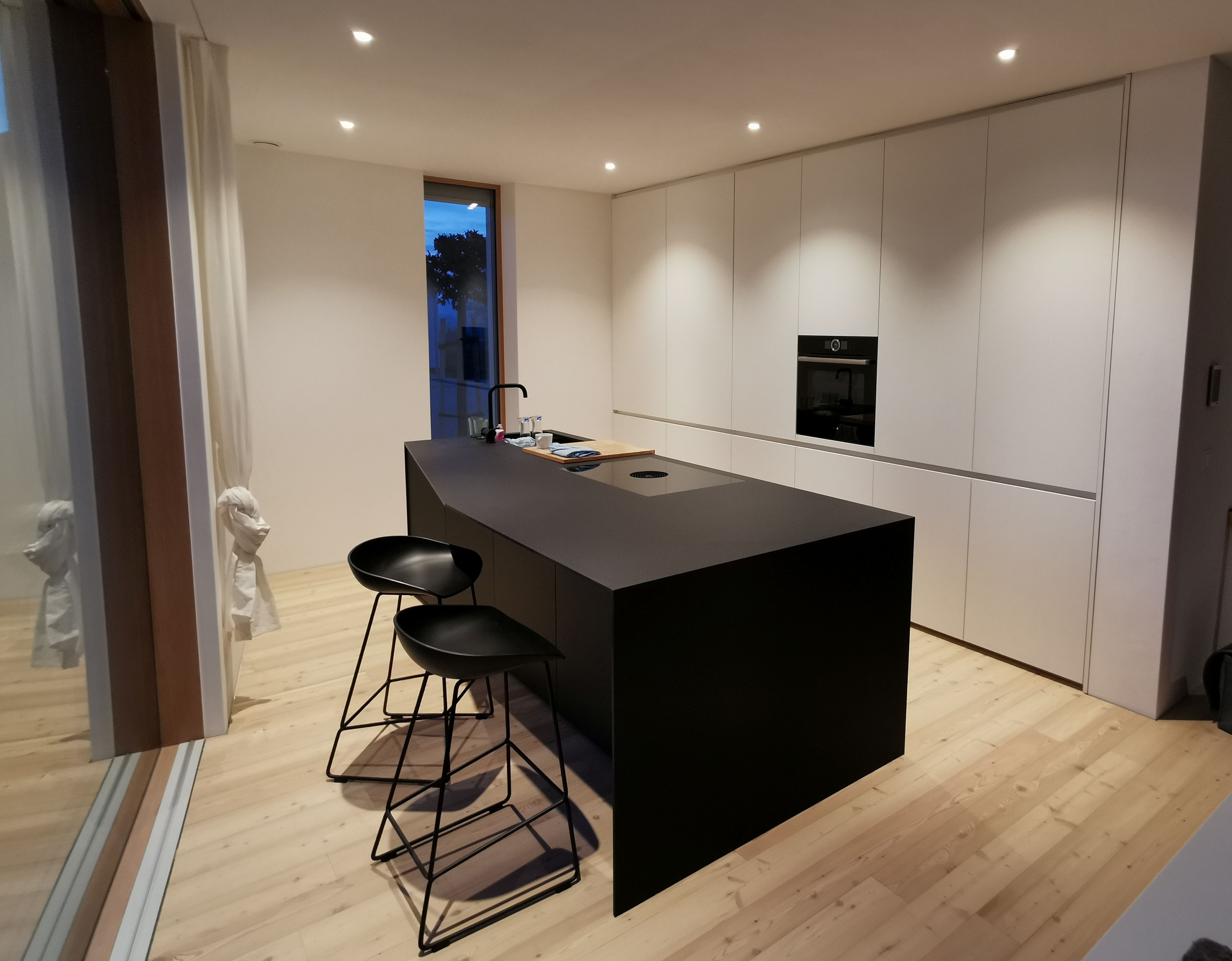 Schwarze minimalistische Insel-Küche mit Barhockern