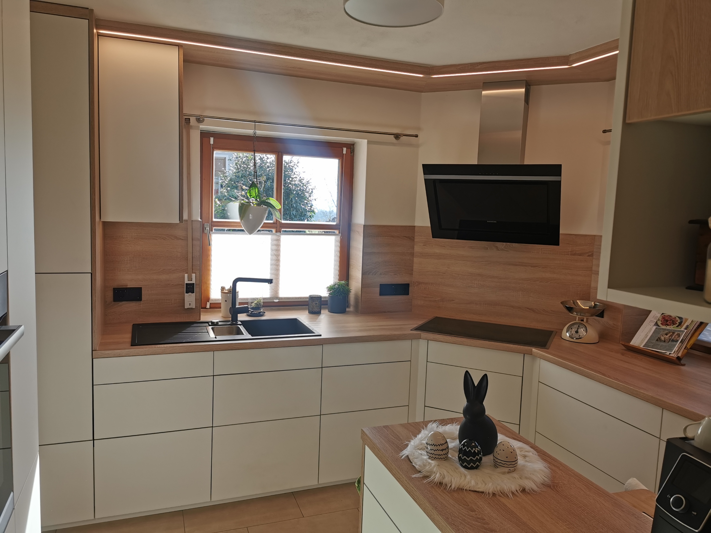 Creme-L-Küche mit warmer Eiche und beleuchteter Decke
